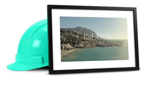 Framed coastal landscape photo with the Cinergy Spaces logo, placed next to a turquoise construction hard hat